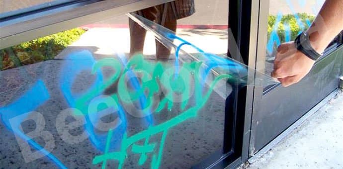Sacrificial anti-graffiti surface protection film being peeled away leaving pristine glass